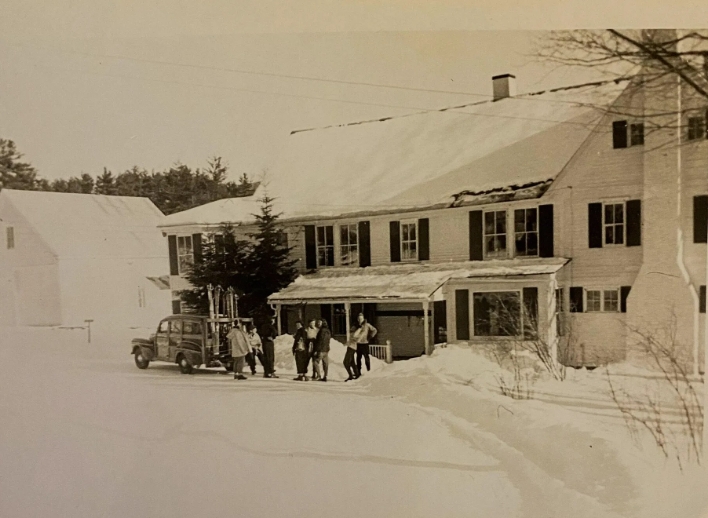 Black and white photo of Cranmore Mountain Lodge covered in snow with an old timey car parked in front