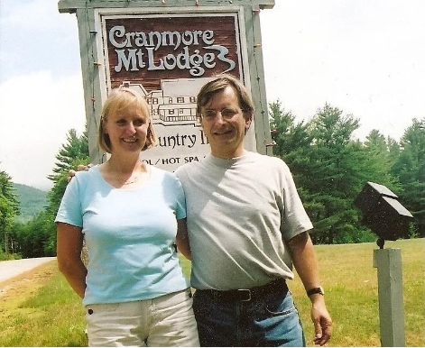 Older couple standing in front of outdoor sign for Cranmore Mountain Lodge