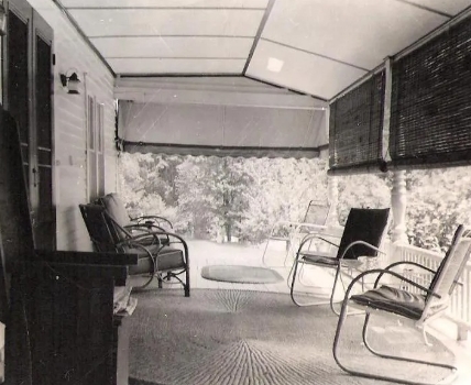 Black and white photo of several chairs on front porch