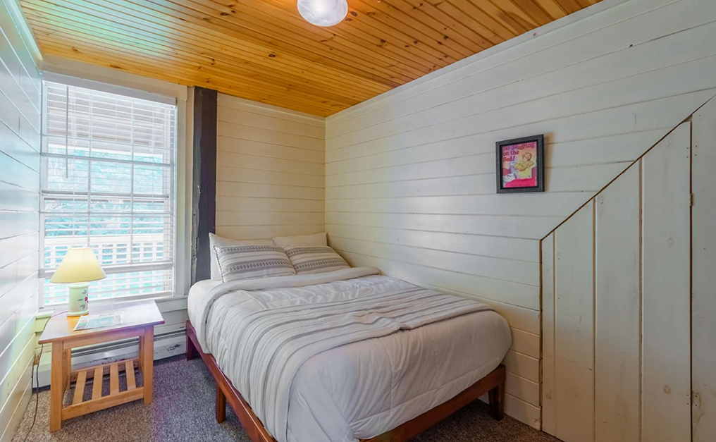 Full bed in corner of small room with a slightly slanted ceiling