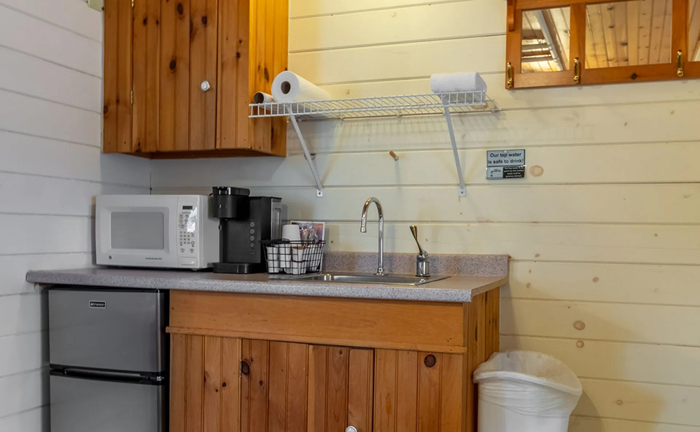 Close up of sink mini fridge and wooden cabinet