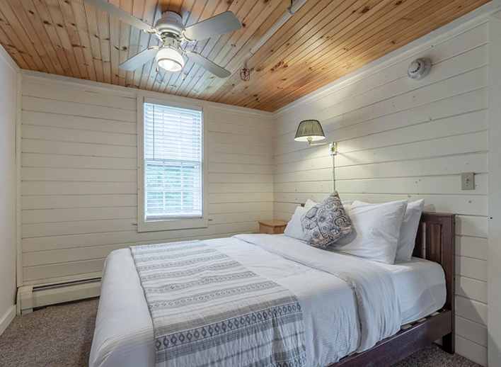 Hotel room with a small window and white wood walls in North Conway