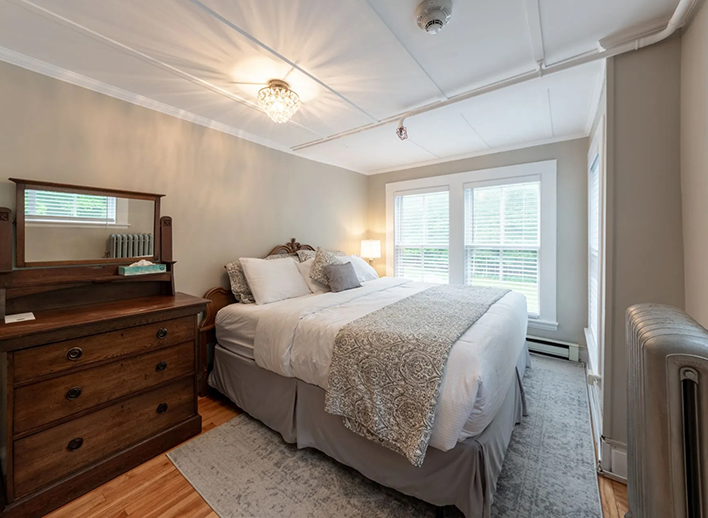 Hotel room with pale yellow walls and an antique wood dresser in North Conway