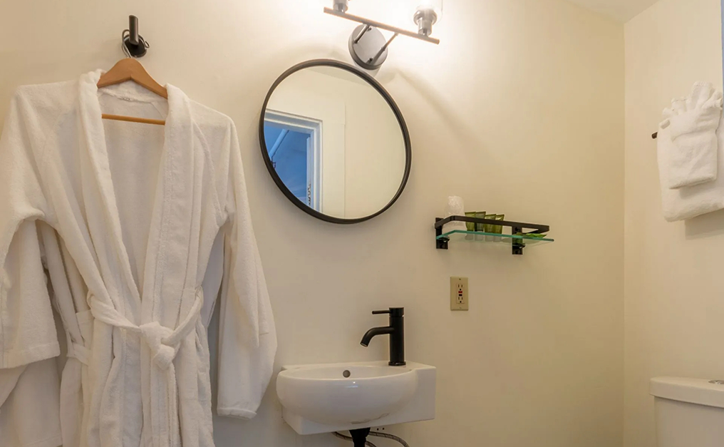 White bathrobe hanging on wall next to circular mirror